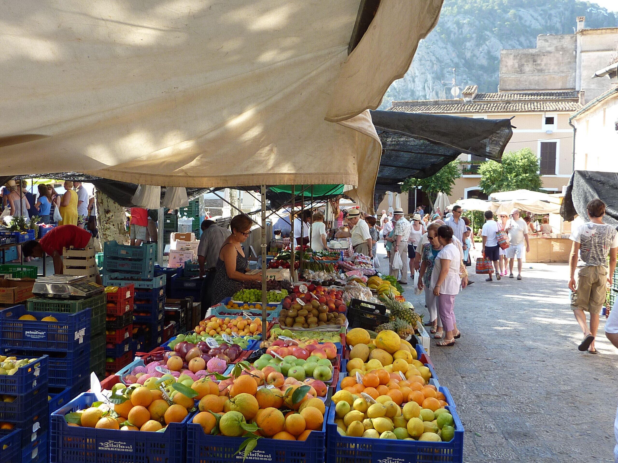A bustling outdoor market with various stalls selling fresh produce like fruits and vegetables.