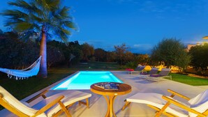 A swimming pool with lounge chairs and a hammock, surrounded by trees and a well-maintained lawn. - Villa Cana Cati Pollensa Town (Pollensa / Pollença)