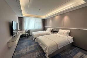 A modern hotel room with two beds, a desk, and a TV.