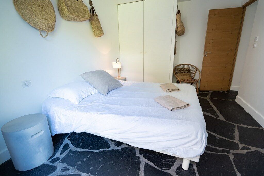 Une chambre à coucher avec un lit, une lampe de chevet, une chaise et une armoire.