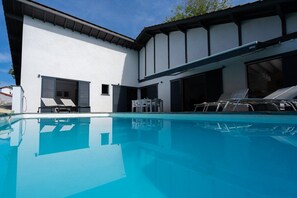 A modern house with a swimming pool, a covered patio, and a garage.