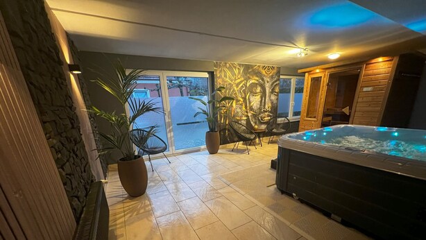 Wellnessbereich mit Whirlpool, Topfpflanzen und einem großen Fenster.