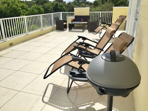 A balcony with outdoor furniture, including chairs and a table, and a grill. - 4BR Townhouse 320 by Ideal Experience VR (Fort Lauderdale)