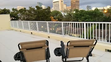 Two foldable chairs on a balcony with a city skyline in the background.