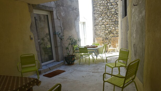 A patio with a table and chairs, a potted plant, and a stone wall.