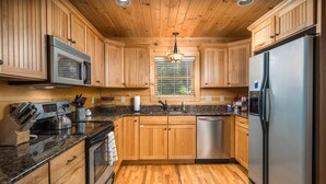 A kitchen with wooden cabinets, a stainless steel refrigerator, a microwave, a stove, and a dishwasher.