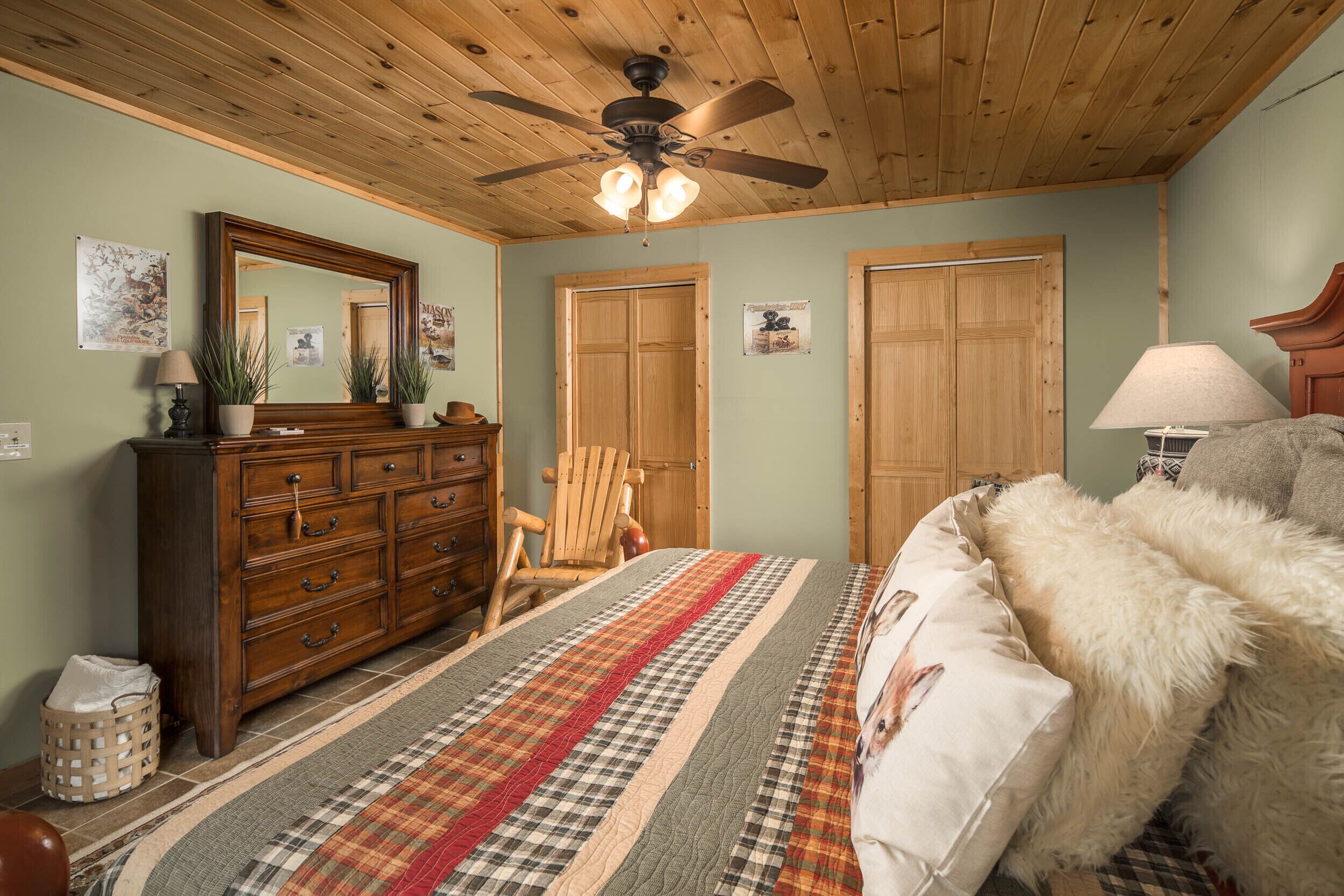 Une chambre avec un plafond en bois, un lit recouvert d’une couverture à rayures, une commode, une chaise et deux portes.
