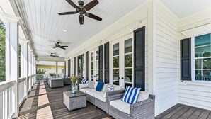 A covered porch with wicker furniture and ceiling fans. - Luxury 2nd Row Home, Chefs Kitchen, Pool, Free Golf, Great for Entertaining (Hilton Head)