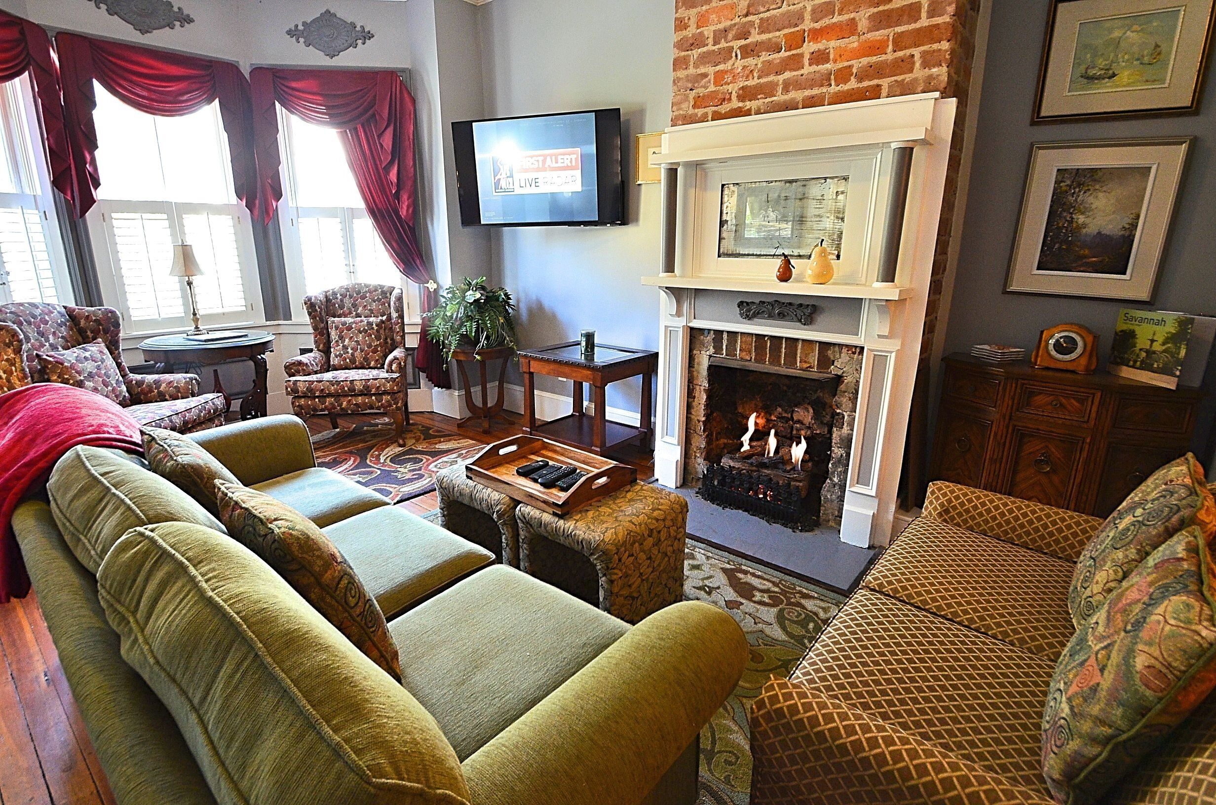 A living room with a fireplace, a television mounted on the wall, and a sofa set.