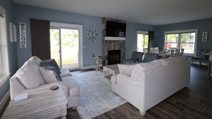 A living room with two white sofas, a fireplace, and a dining area with a table and chairs. - Relax by Lake Michigan within a 5-min stroll (South haven)