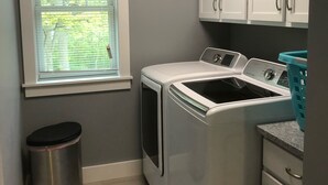 A laundry room with a washing machine, a dryer, a trash can, and a window with blinds. - Relax by Lake Michigan within a 5-min stroll (South haven)