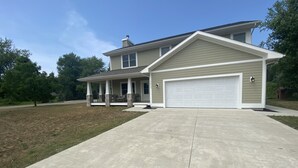 A two-story house with a covered porch and a garage. - Relax by Lake Michigan within a 5-min stroll (South haven)