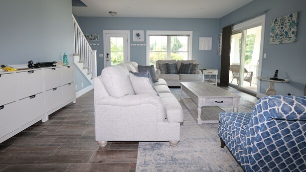 A spacious living room with a white sofa, a blue patterned sofa, and a white coffee table. There is a staircase with white railings leading to another level. - Relax by Lake Michigan within a 5-min stroll (South haven)