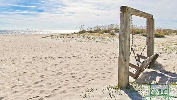 Ein Sandstrand mit einer Holz-Schaukel.