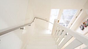 A white staircase with a metal handrail and wooden steps leading to a landing. - Casa Grande - An amazing house 1 km from Amsterdam (Landsmeer)
