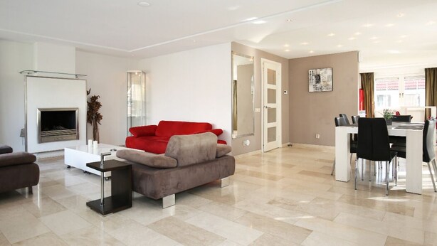 A modern living room with a fireplace, a red and grey sofa, a coffee table, and a dining area with chairs and a table. - Casa Grande - An amazing house 1 km from Amsterdam (Landsmeer)