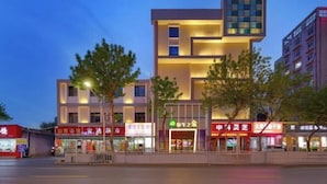 A modern building with multiple floors, featuring illuminated signage and storefronts. - Snail House Hotel (Zhengzhou)