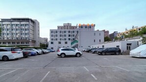 A parking lot with several cars, surrounded by multi-story buildings with commercial and residential uses. - Snail House Hotel (Zhengzhou)