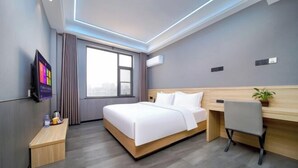 A modern hotel room with a bed, desk, chair, and a TV on the wall. - Snail House Hotel (Zhengzhou)