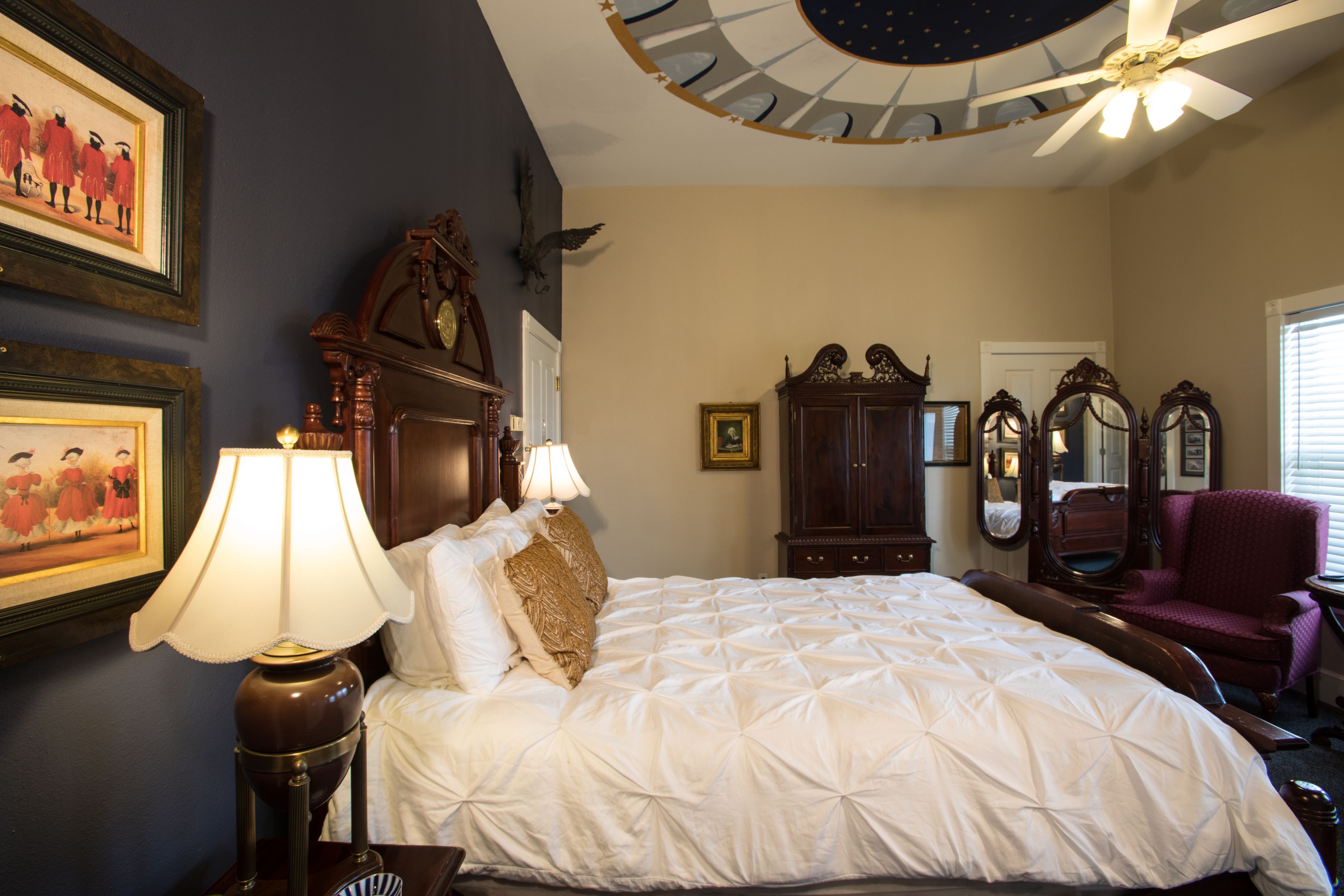 A bedroom with a large bed, a ceiling fan, and a chandelier.