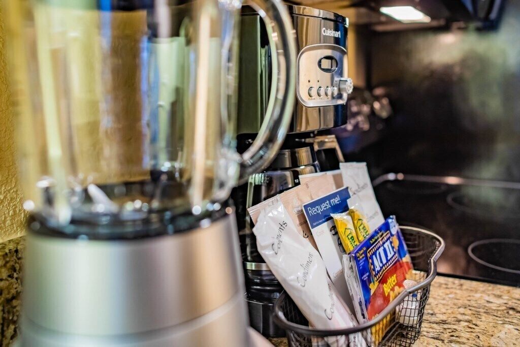 Eine Küchenzeile mit Kaffeemaschine und einem Korb voller Lebensmittel.