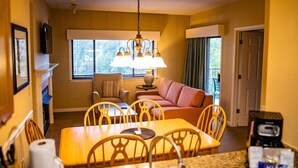 A compact hotel room with a dining area, a sofa, and a television.