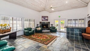 A spacious lounge with a fireplace, leather seating, and a patterned rug. - LUXURY 2br/2baRemodel in the HEART of Scottsdale! HEATED POOL, GYM, TENNIS COURT (Scottsdale)