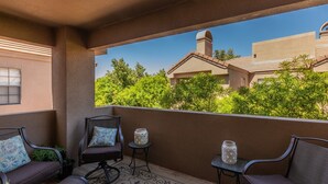 A balcony with a view of neighboring houses, a chair, a small table, and a decorative vase. - LUXURY 2br/2baRemodel in the HEART of Scottsdale! HEATED POOL, GYM, TENNIS COURT (Scottsdale)