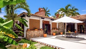 Un bâtiment de style traditionnel, doté d’une façade en pierre, d’un toit en tuiles et d’un patio aménagé avec des sièges extérieurs.