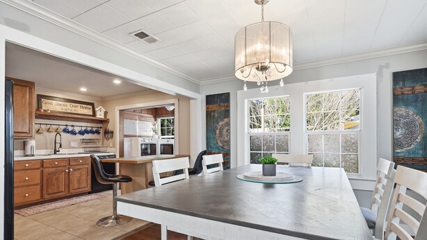 A kitchen with a large island, wooden cabinets, and a chandelier.