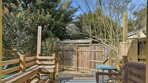 A wooden deck with a bench, a table, and a chair.