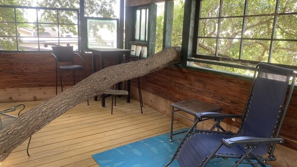 Een houten terras met een hangmat, opklapbare stoelen en een blauwe mat.