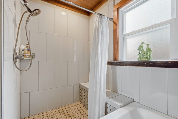 Une salle de bain équipée d’une douche, d’une baignoire et d’une fenêtre agrémentée d’un objet décoratif.