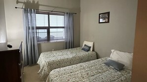 A room with two beds, a window with curtains, a dresser, and a framed picture on the wall. - 2nd Floor 'Sky Rise Vista' - Pool Access! (Sugar Mountain)