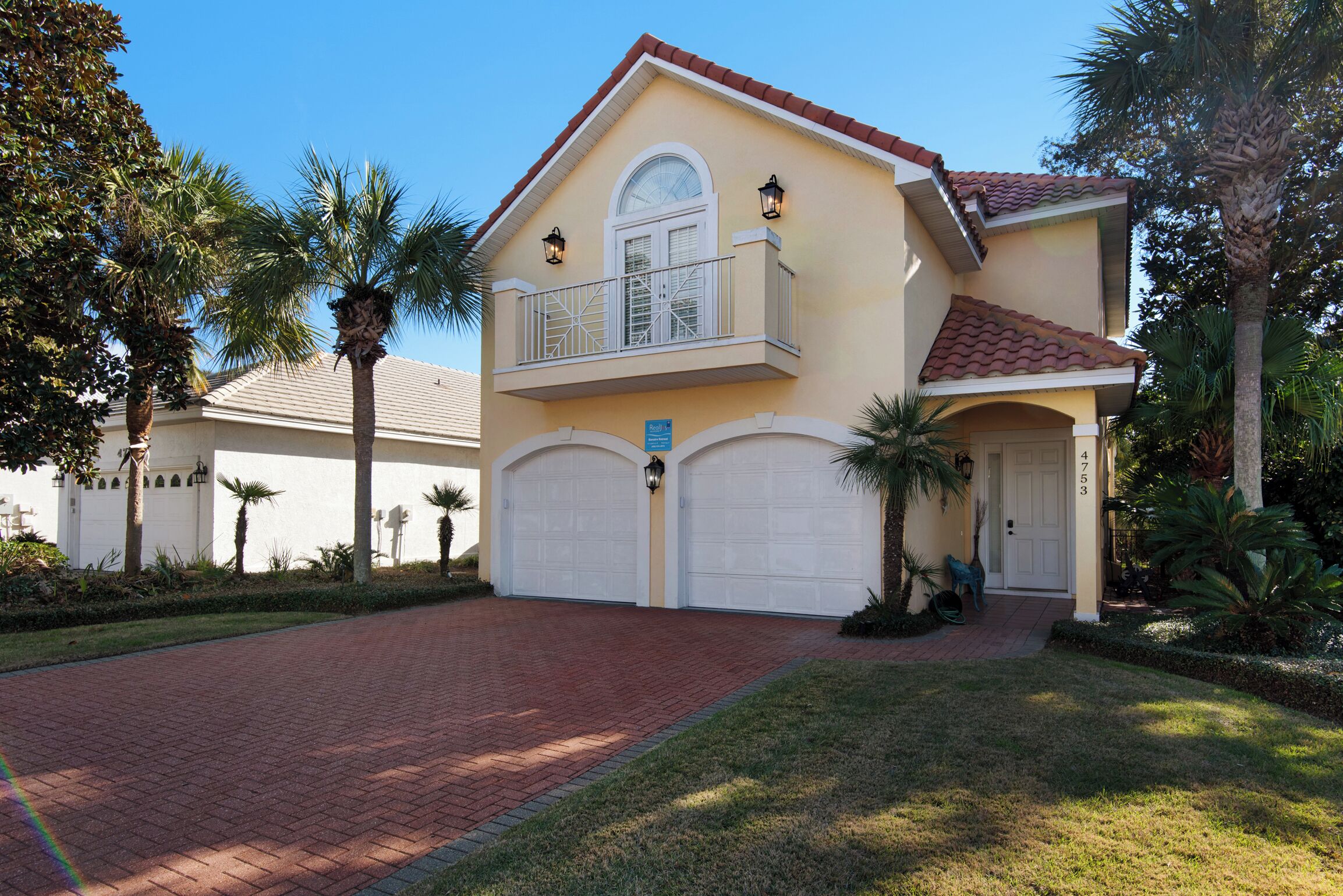 A two-story house with a balcony, a garage, and a well-maintained lawn.