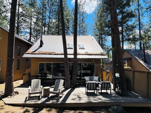 A cabin with a deck, outdoor seating, and a large window.