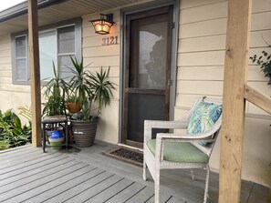 A porch with a wicker chair and potted plants.