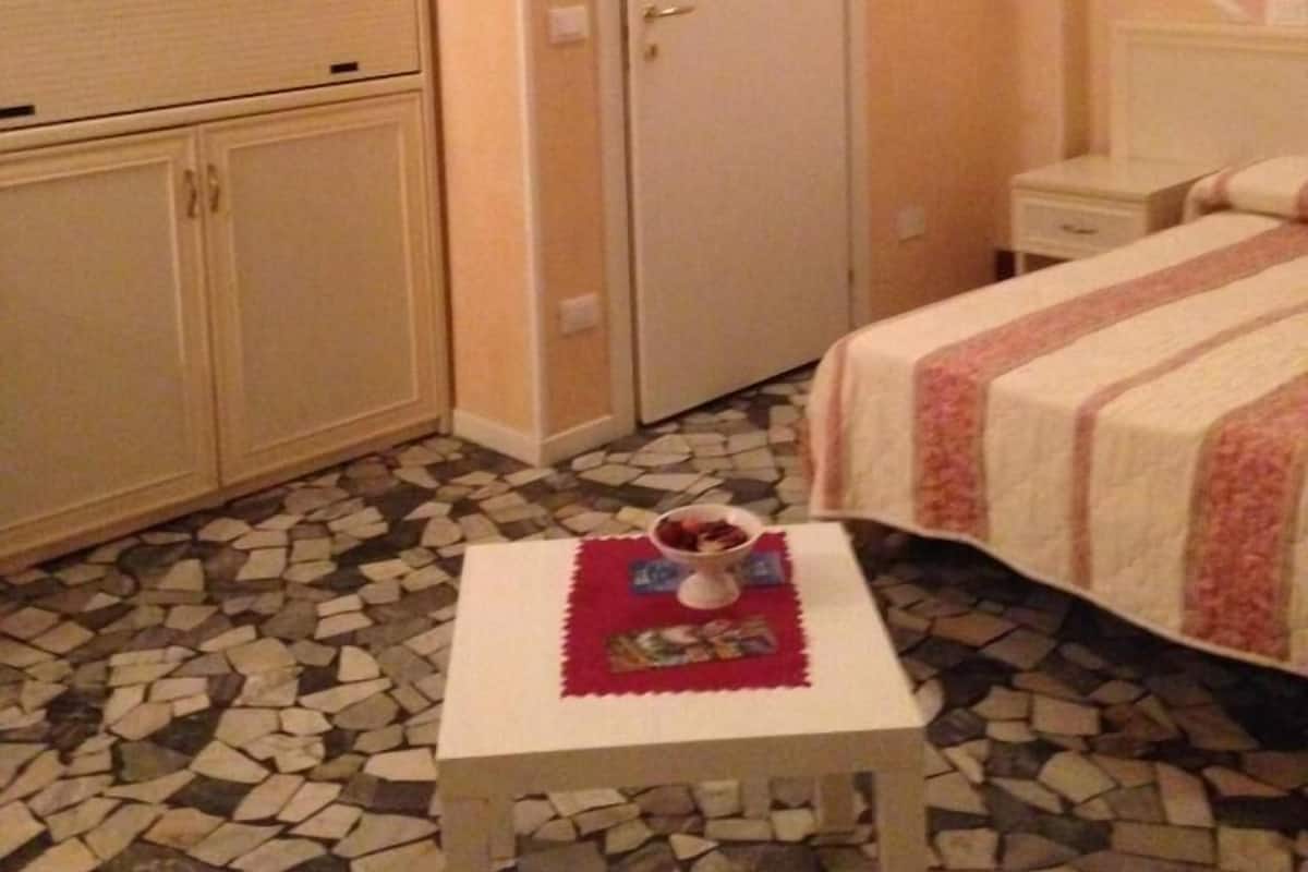 Een hotelkamer met een bed, een kleintje tafeltje met een fruitschaal, een kledingkast en een deur.