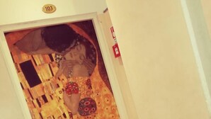 Una scala con un muro decorato e una porta con una targa.