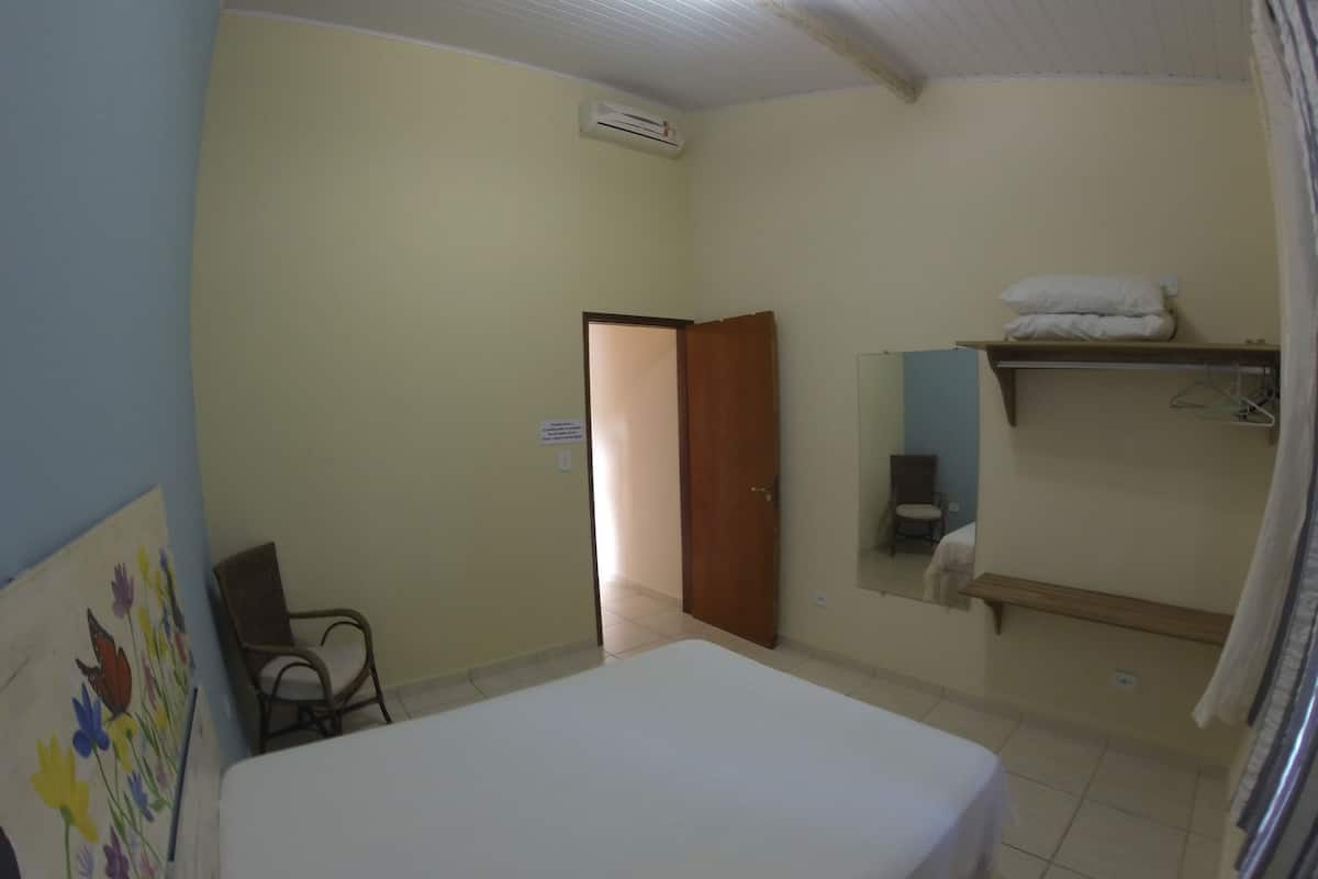 Een hotelkamer met een bed, een stoel, een spiegel en een plank met handdoeken.