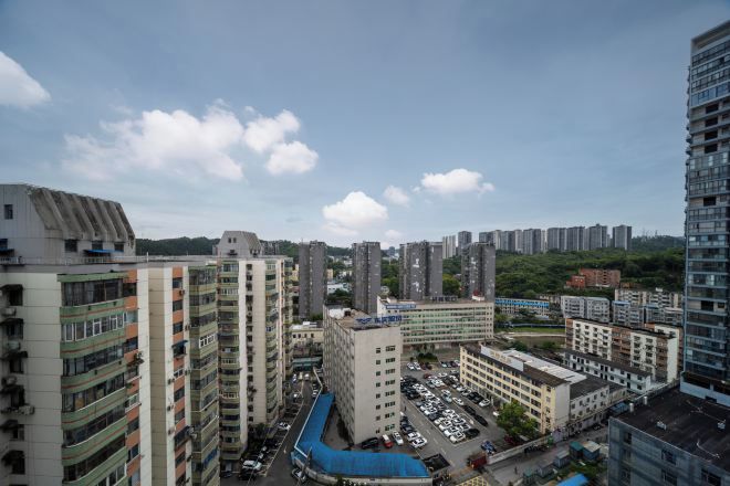 A high-rise residential building complex with multiple apartment buildings, a parking area, and a blue-roofed structure.