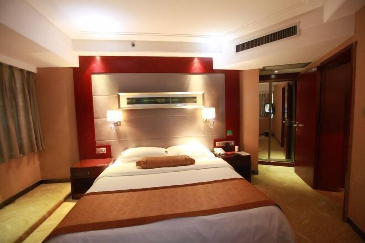 Ein Hotelzimmer mit einem großen Bett, Nachttischen, einem Spiegel und einer Tür.