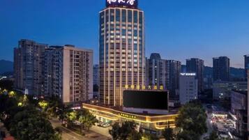 A high-rise hotel with a prominent sign, surrounded by other buildings and a parking area.