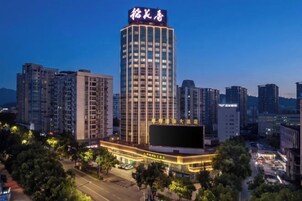 Un hotel de gran altura con un letrero llamativo, rodeado de otros edificios y un estacionamiento.