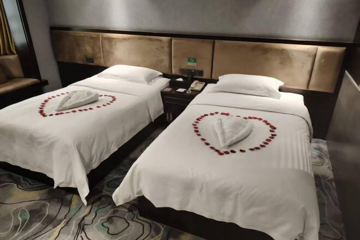 Ein Hotelzimmer mit zwei Betten, einem Nachttisch, einem Sessel und einer Kopfteil.