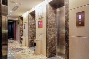 A hotel corridor with marble walls, elevators, and a carpeted floor. - Bonway International Hotel (Shiyan)