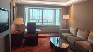A hotel room with a large window, a sofa, a chair, a TV, and a lamp. - Bonway International Hotel (Shiyan)