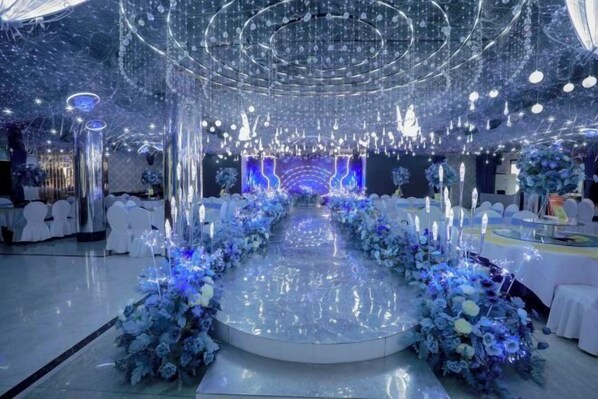 A venue with a central stage, surrounded by white chairs and floral arrangements. - Bonway International Hotel (Shiyan)