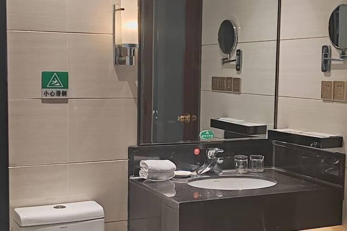 Ein Badezimmer mit Waschbecken, Spiegel, Handtuch und Toilette.