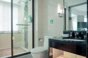 A modern bathroom with a glass shower enclosure, a toilet, a sink with a mirror, and a window with blinds. - Bonway International Hotel (Shiyan)